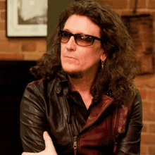 a man with long curly hair wearing a leather jacket and sunglasses