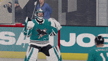 a hockey player stands on the ice in front of an advertisement for joe 's
