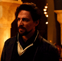 a man with a beard wearing a black jacket and a white shirt