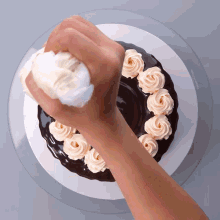 a person is frosting a chocolate cake with roses