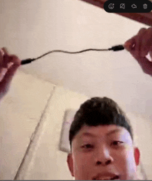 a man is holding a cable in his hands and a screenshot of his face is visible