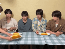 a group of young men are sitting at a table with plates of food and one of them is wearing a shirt that says 13 on it
