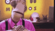 a puppet is wearing a pink shirt and suspenders and making a face .