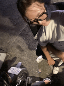 a woman wearing glasses is standing next to a motorcycle with a license plate that says tcl - j