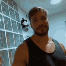 a man in a black tank top is standing in front of a shelf with a bottle of gin on it