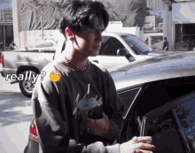 a man standing next to a car with a smiley face on his chest and the word really on the bottom