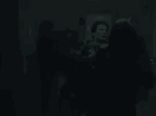 a group of people are standing in the dark in a room .