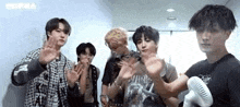 a group of young men are standing next to each other in a room with a fan .