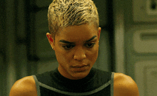 a woman with short blonde hair is wearing earrings and a black tank top