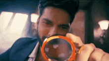 a man with a beard is looking through a magnifying glass at something