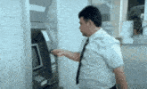 a man in a white shirt and tie is inserting a credit card into an atm machine