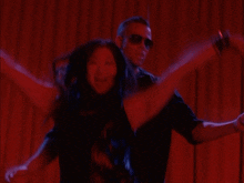 a man and a woman are dancing in a dark room with red lights behind them
