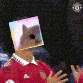 a man wearing a red shirt has a cat on his head .