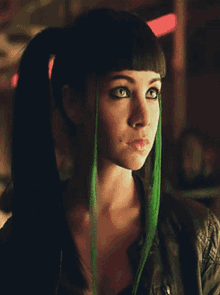 a woman with a ponytail and green streaks in her hair