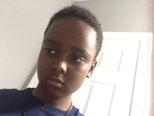 a young boy wearing a blue shirt and a gold necklace looks at the camera