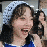 a woman wearing a blue hat and a blue tank top is smiling .