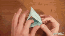 a person is folding a piece of paper and the words made in animotica are visible