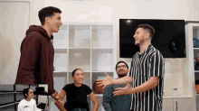 a group of people are standing in a room with a man wearing a striped shirt that says visa