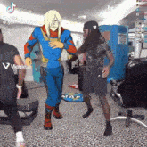 a man in a blue superhero costume is standing next to another man in a gym .