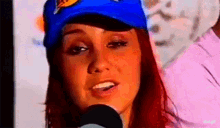 a woman wearing a blue hat is talking into a microphone