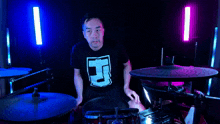 a man wearing a shirt with the letter j on it is playing drums