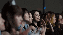 a group of women are sitting in a theater applauding .