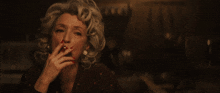 a woman with red nails is smoking a cigarette in a dark room