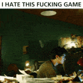 a man sits at a table with the words i hate this fucking game on the bottom