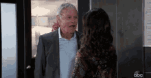 a man in a suit and a woman in a dress are standing next to each other in a room .