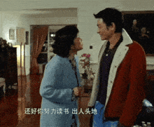 a man and woman are standing next to each other in a living room with chinese writing on the wall