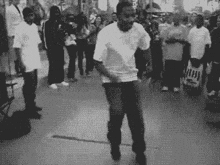 a man in a white shirt is dancing in front of a crowd of people