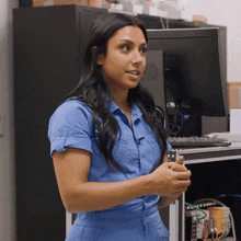 a woman in a blue jumpsuit stands in front of an hp computer