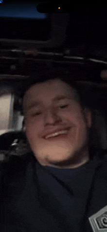 a man wearing a black shirt with the letter c on it smiles