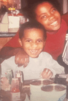 a woman and a child are posing for a picture and the woman is wearing a red shirt and the child is wearing a white shirt