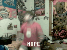 a person in a red shirt is dancing in a room with posters on the wall including one that says hope