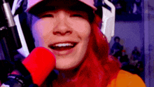 a woman with red hair is smiling and holding a red microphone in front of her face