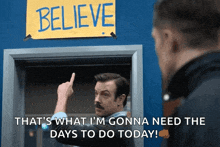 a man is pointing at a sign that says believe that 's what i 'm gonna need the days to do today