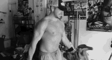 a man without a shirt is riding an exercise bike in a room with posters on the wall .