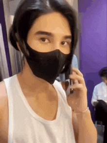 a man wearing a mask and talking on a cell phone .