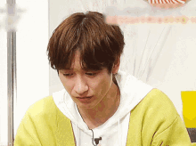 a young man wearing a yellow sweater and a white shirt