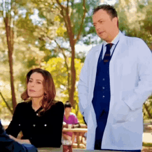 a man in a lab coat stands next to a woman in a black sweater .