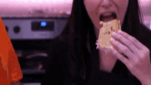 a woman is eating a piece of food in front of a stove with a digital display that says ' 00 '