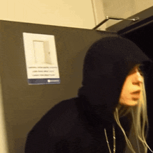 a person wearing a black hoodie is standing in front of a door with a sign on it that says ' closed '