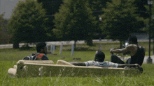 three men laying on a couch in a grassy field