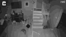 a black and white photo of a living room with stairs and a nest logo