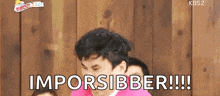 a man in a pink shirt says " imporsibber !!! " in front of a wooden wall