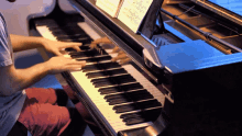 a man playing a piano with a sheet of music behind him