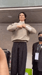 a man in a sweater and striped pants is standing on stilts with his hands on his chest .
