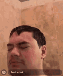a man in a shower with his eyes closed and a send a chat button in the corner