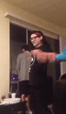 a man with red hair is dancing in a living room with other people .